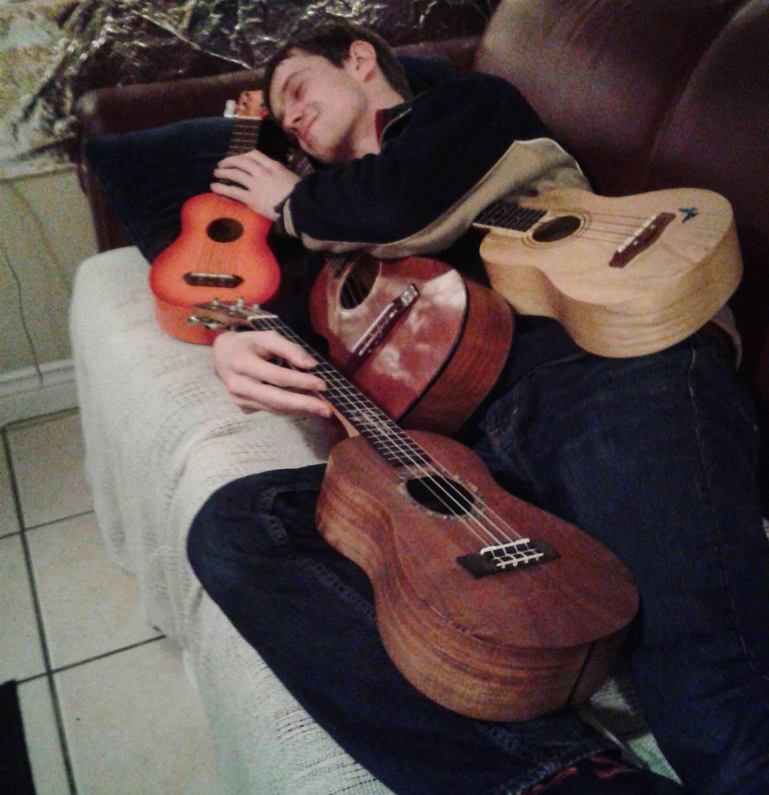 Mark cuddling with four ukuleles